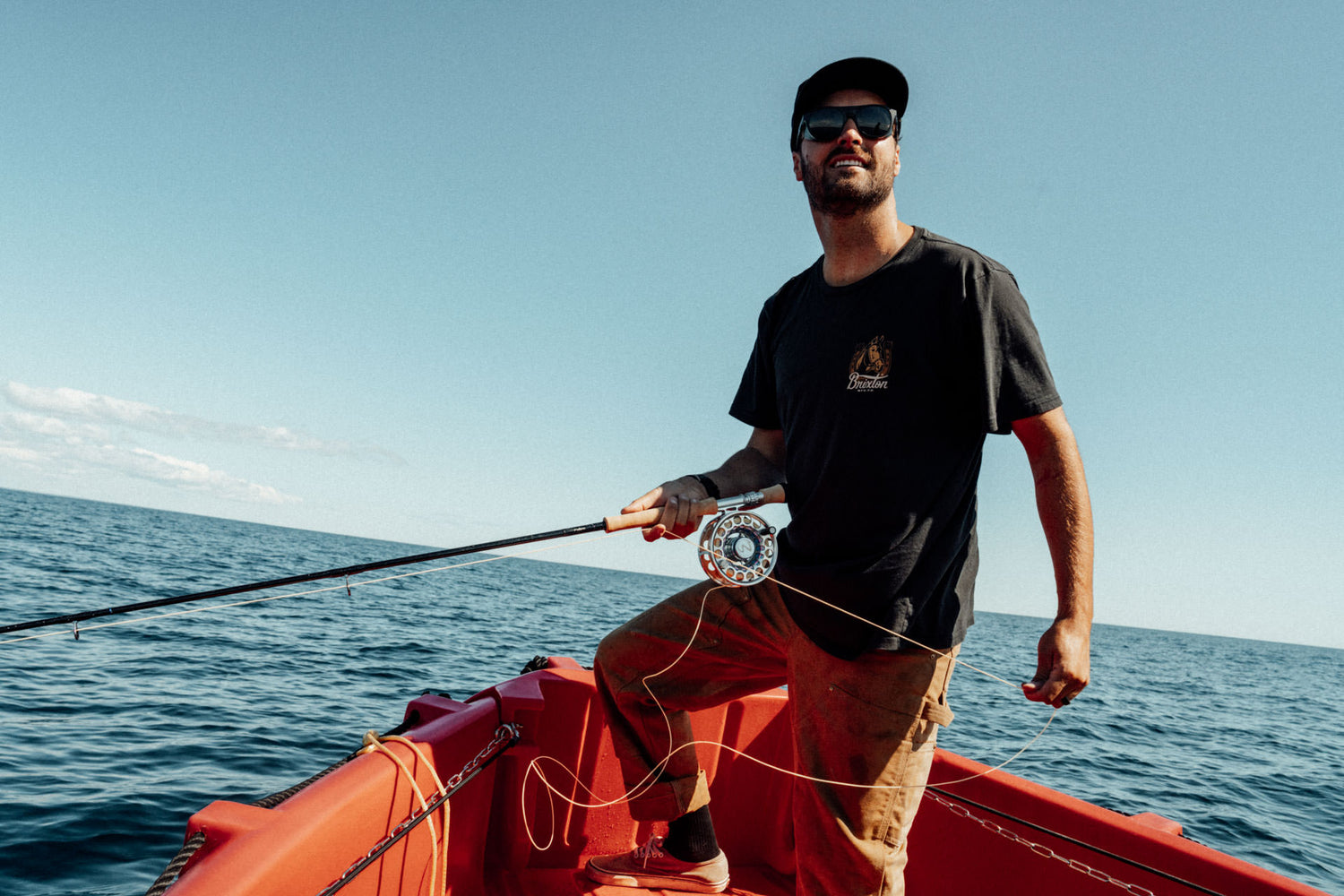 Pro surfer Logan Landry fishing from a boat in Cow Bay, Nova Scotia.