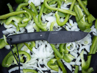 The Hell Gap fixed blade camping knife on a pile of cut vegetables.