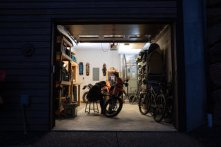 A man working on his dirt bike in the garage at night.