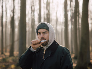 A man eating an apple slice off the blade of his Wayland classic Barlow slip joint folding knife in the Ghost Forest of Germany.