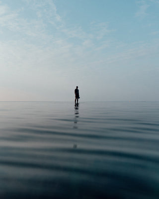 A photographer standing on a shallow sandbar in the North Sea.