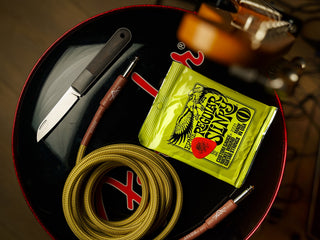The Wayland classic Barlow EDC folding slip joint black and stainless pocket knife on a bass drum with music equipment. 