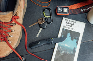 The Carter EDC folding slide lock pocket knife on a tail gate with outdoor gear and a Hardin keychain carabiner.