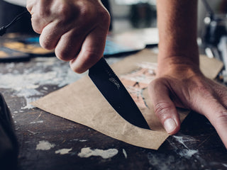 A man cutting paper with the Hell Gap fixed blade camping knife.