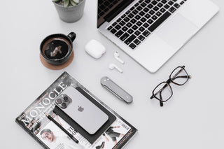 The Wells EDC flipper button lock folding pocket knife in raw aluminum on a desk with a apple lap top.