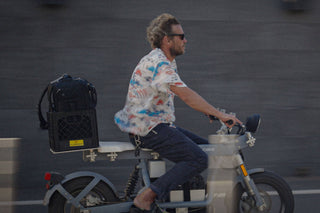 Professional skateboarder and photographer Arto Saari riding an electric bike with his camera gear in tow.