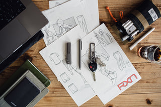 The Bolen titanium EDC twist pen with a pocket knife and a carabiner keychain on a desk.