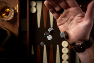 The TJB titanium dice being tossed onto a backgammon board.