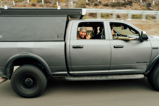 A man flashing the peace sign on from a truck on the road in Baja California.