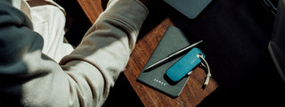 A utility knife and pen on a desk.