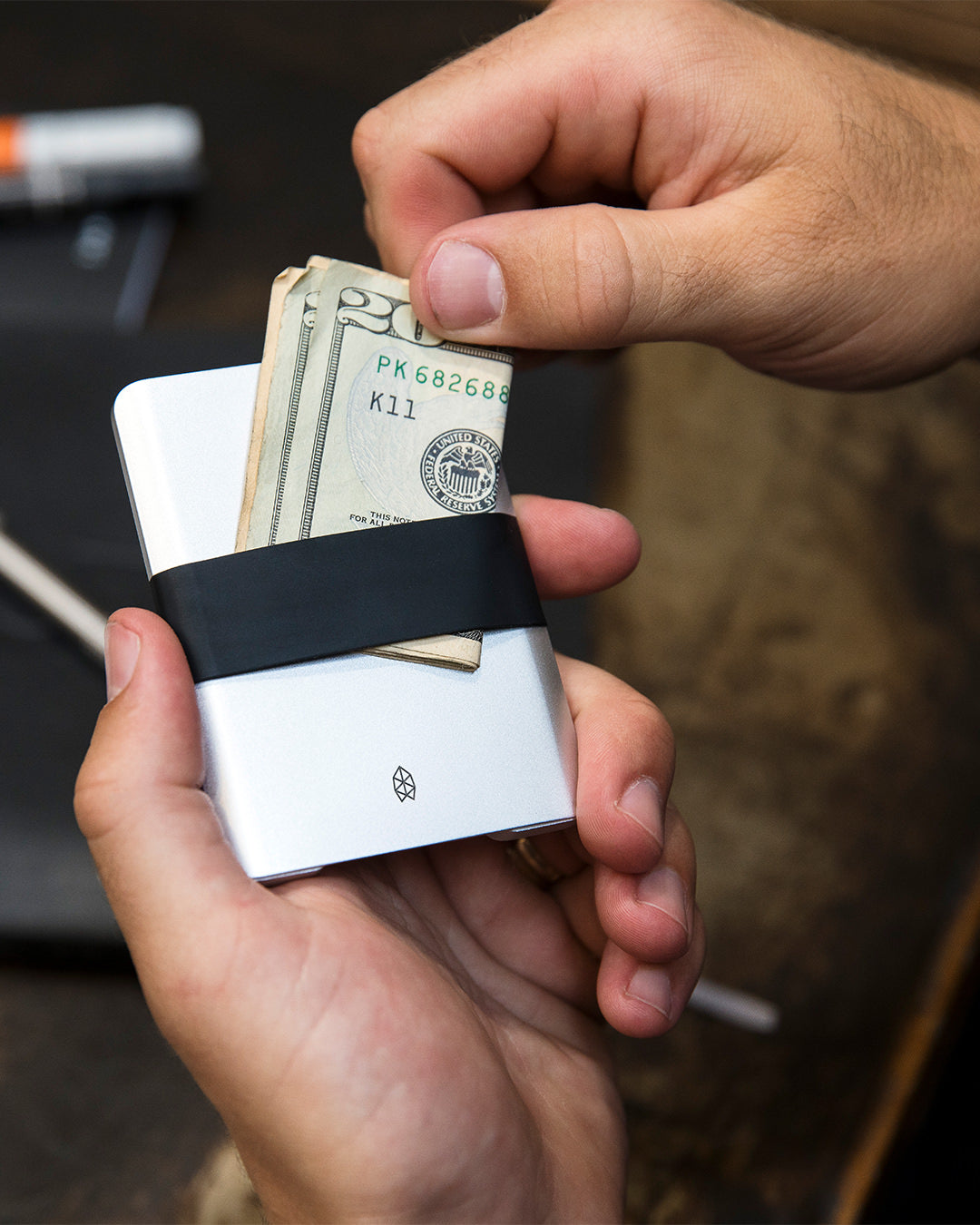 A person sliding a cash into the silicon band of the Lowe minimalist wallet.