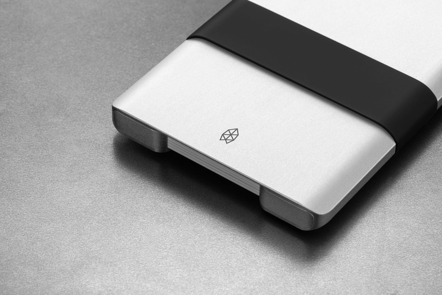 The Lowe minimalist card holder wallet in silver and black on a steel surface