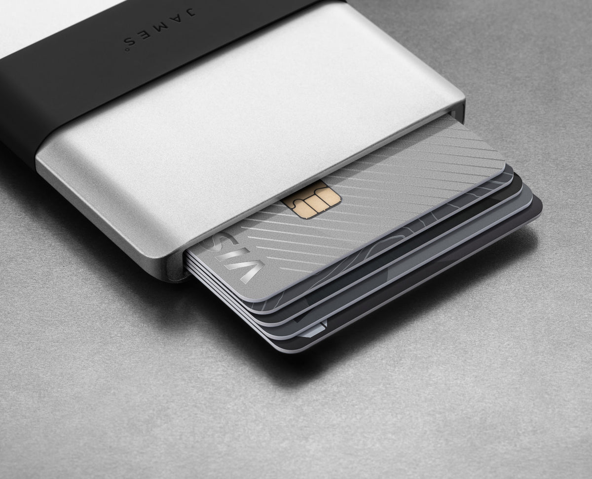 The Lowe minimal card holder wallet in Silver and Black with cards showing on a steel surface.