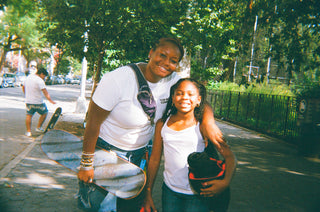 Two girl skaters hugging on the sidewalk.