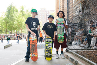 Three kids holding their skateboards in front of them.