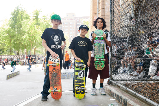 Three kids holding their skateboards in front of them.