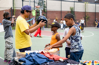 A mentor helping get kids set up with gear to skateboard.