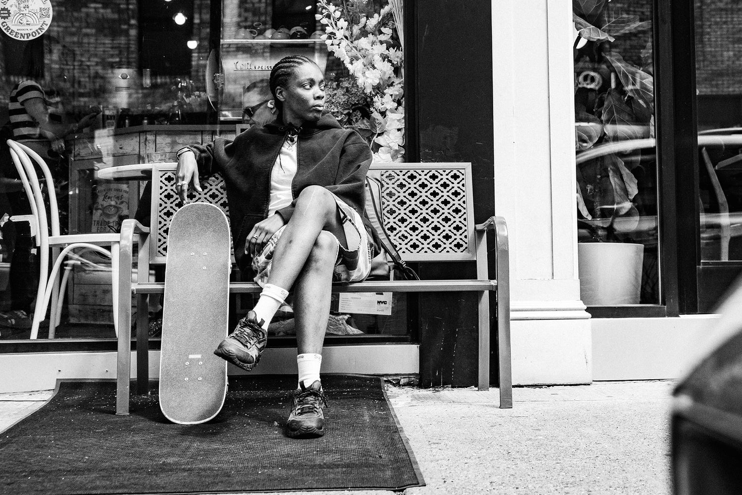 Professional skateboarder Beatrice Domond sitting on a bench on a New York street.