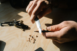A person using the Ellis ultra slim pocket knife to sharpen a pencil.