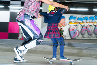 Pro skater Beatrice Domond helping a young girl learn how to skateboard.