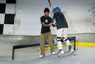 A man helping a young skater learning how ride.
