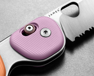 The pivot of Redstone slide lock serrated folding pocket knife in Sherbet and Pink Haze.