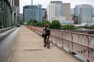 A woman riding her bike across a bridge towards Portland, Oregon.