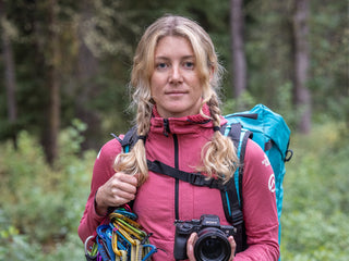 Professional rock climber and photographer Savannah Cummins with her climbing gear in the woods.