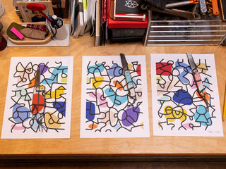 A group of signed prints from artist and skateboarder Sebo Walker with his collab knives on top.